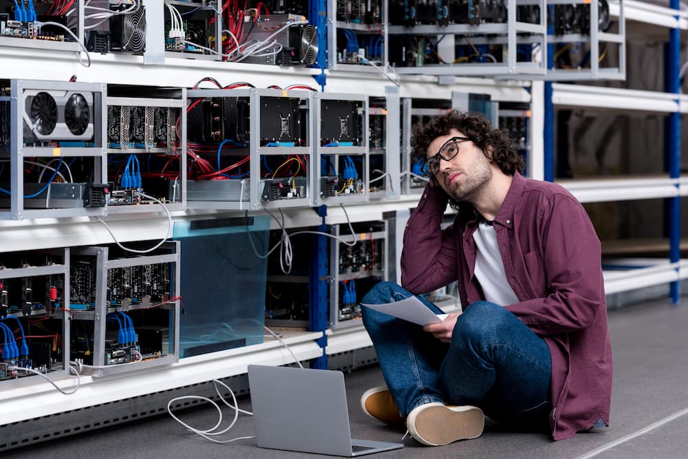 Man sitting on the floor in front of crypto mining equipment